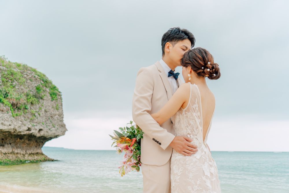 ビーチでハグし、新郎が新婦の頭にキス
